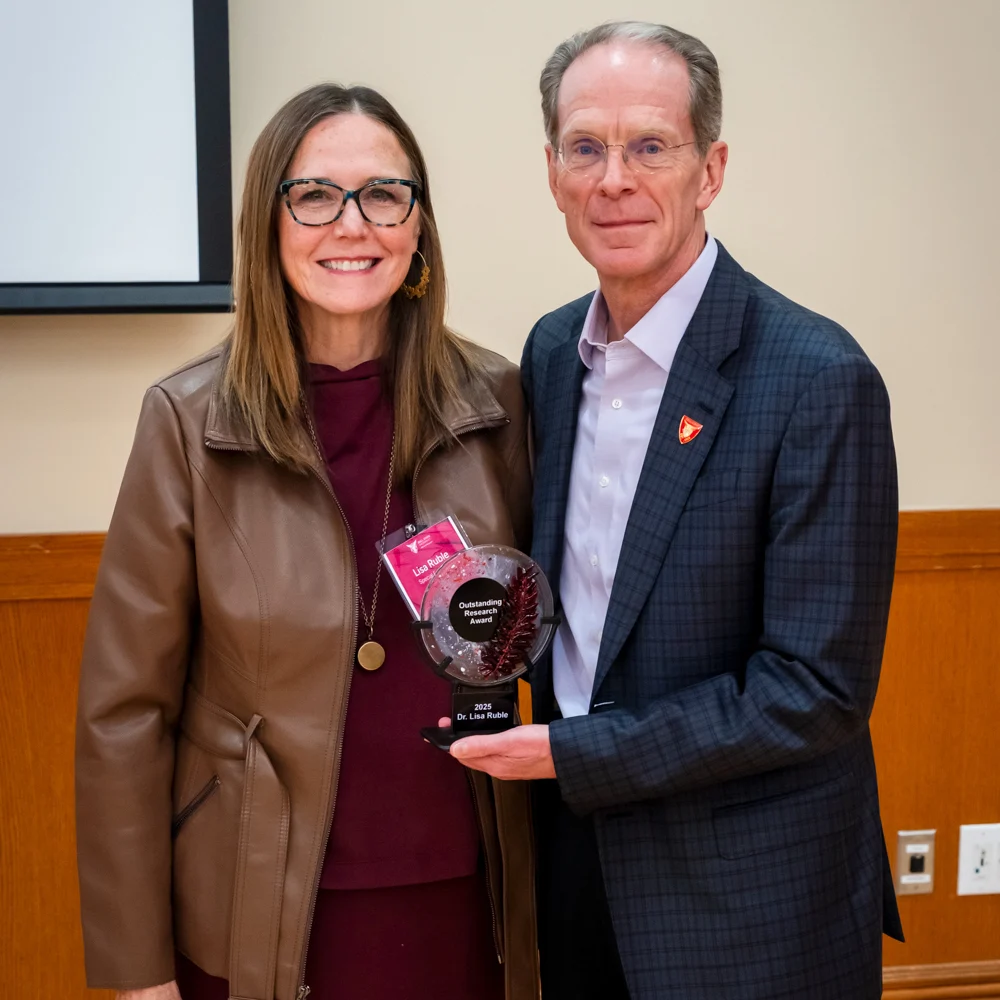 Dr. Lisa Ruble receiving the Outstanding Research Award